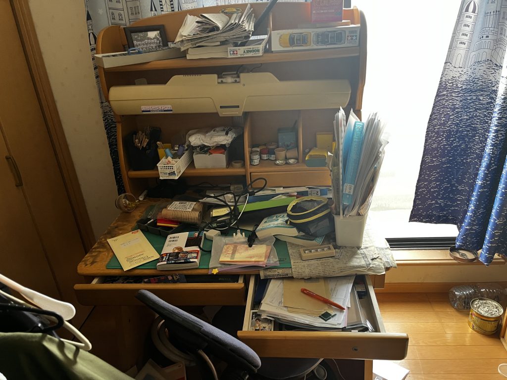 床一面にゴミと雑貨が散乱した洋室。不用品回収が必要な状態。